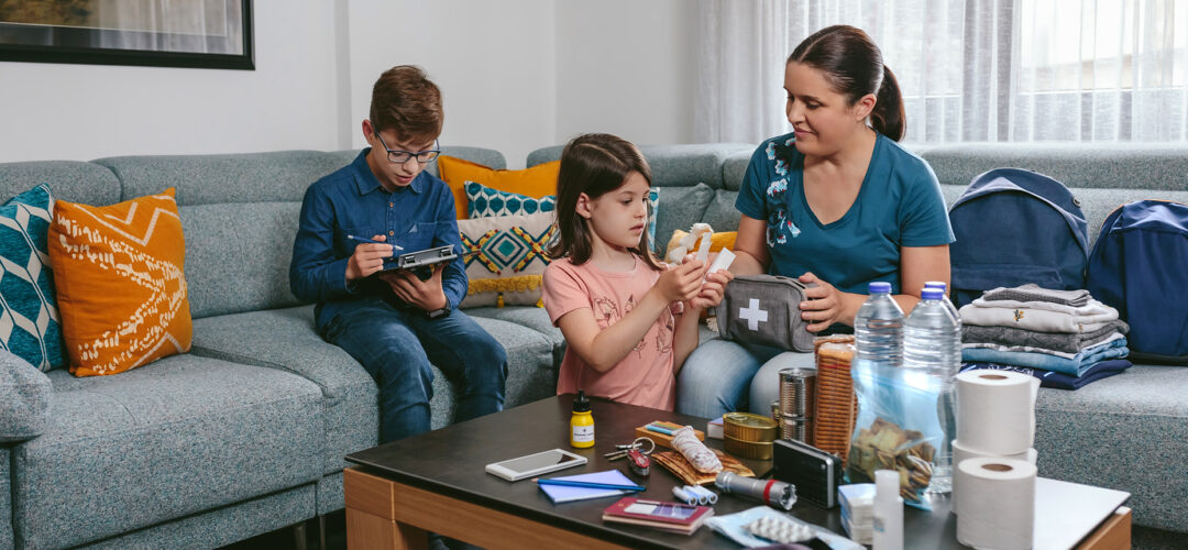 Mom and daughter sitting by table with a collection of items for emergency situations